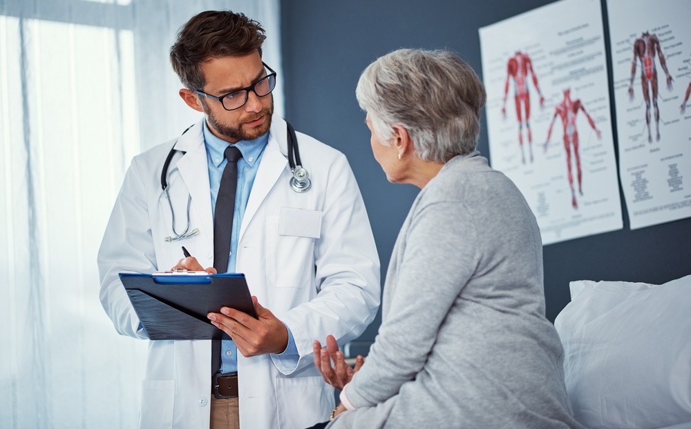 A team of doctors and nurses are working to treat a female patient in the patient's room.